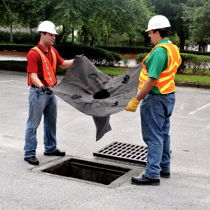 Worker installing an UltraTech Oil and Sediment drain guard in a storm drain catch basin